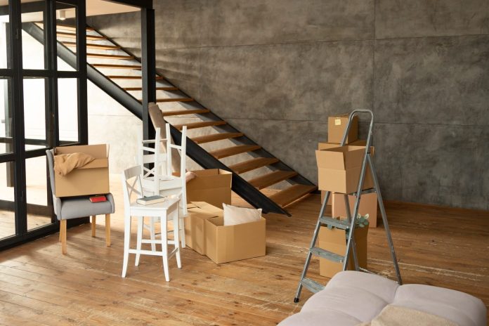 Local diáfano con suelo de madera y escalera, convertido en vivienda durante la mudanza